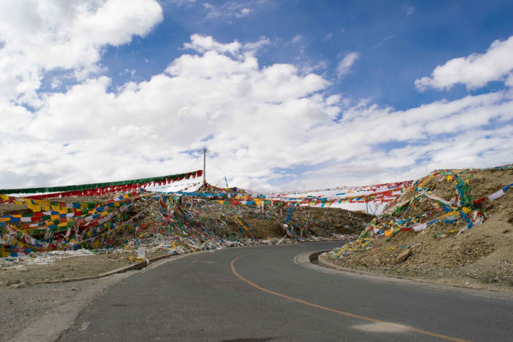 Estrada Lhasa-Shigatse com bandeirinhas de oração. Turismo no Tibet. Budismo tibetano.