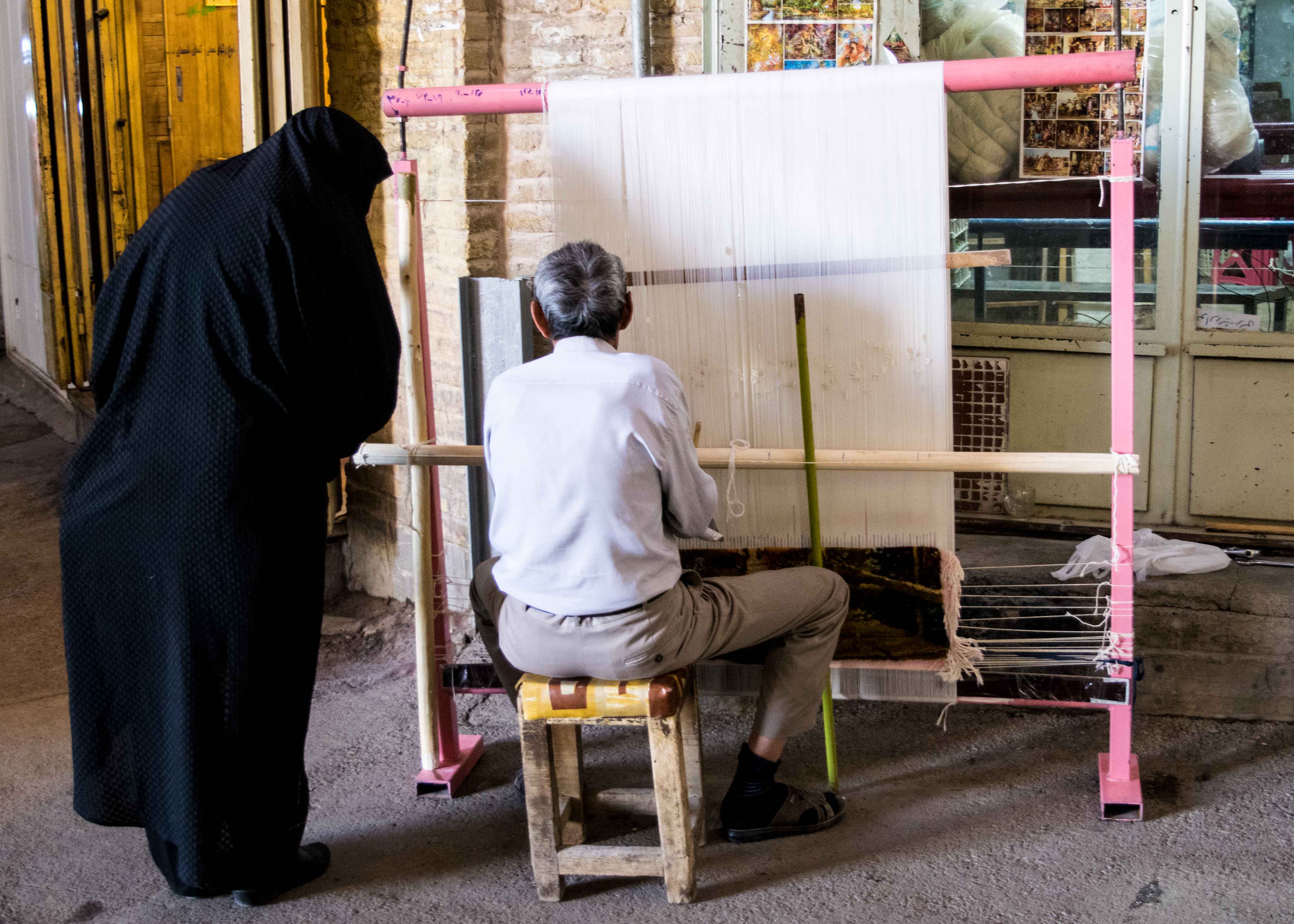 Comprar no Irã: senhor fazendo um dos famosos tapetes persa em um bazzar.